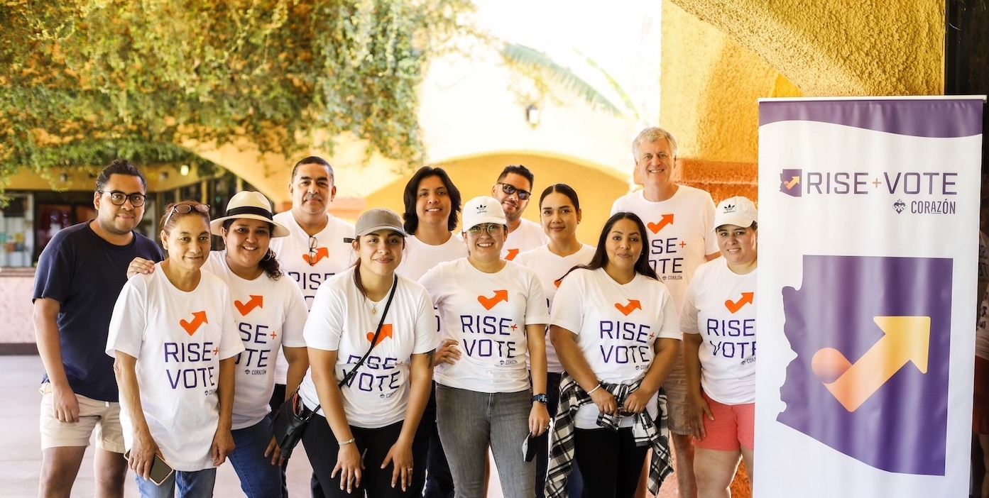 twelve adults of all ages wearing matching t-shirts that say rise and vote